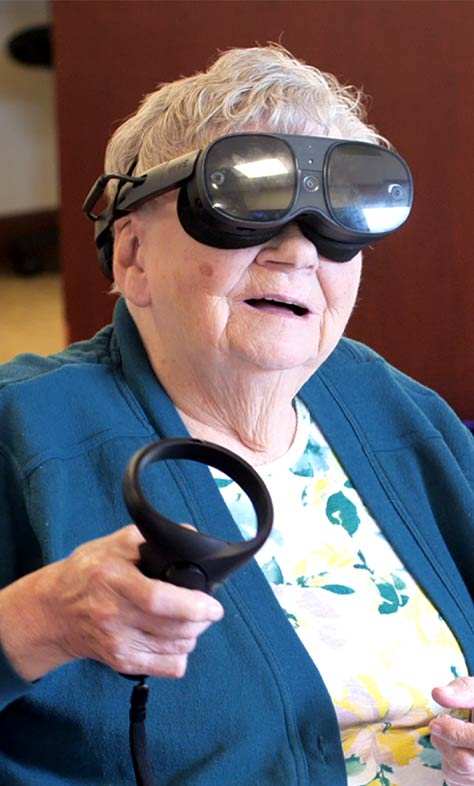Smiling woman wearing black virtual reality glasses, engaged in an immersive therapy experience.